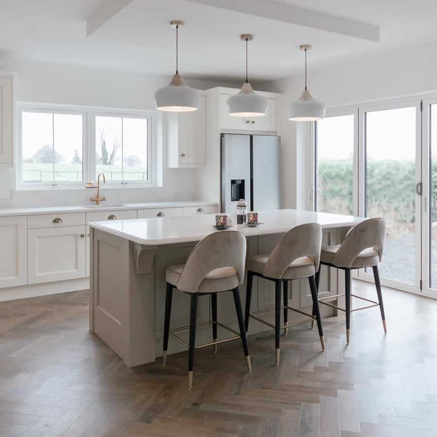 Spacious kitchen with velvet stools and white pendants