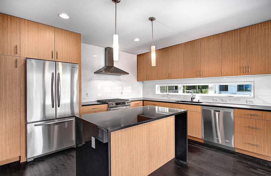 Modern kitchen with wooden cabinets, stainless steel appliances, and black countertops