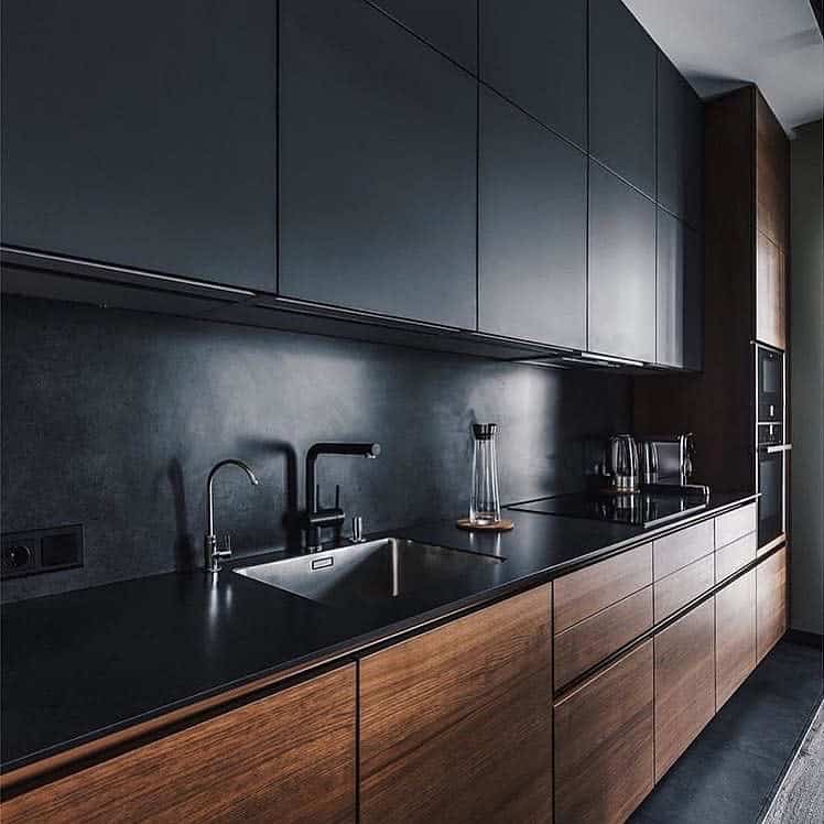 Modern kitchen with dark cabinets, a sink, and sleek appliances on black countertops