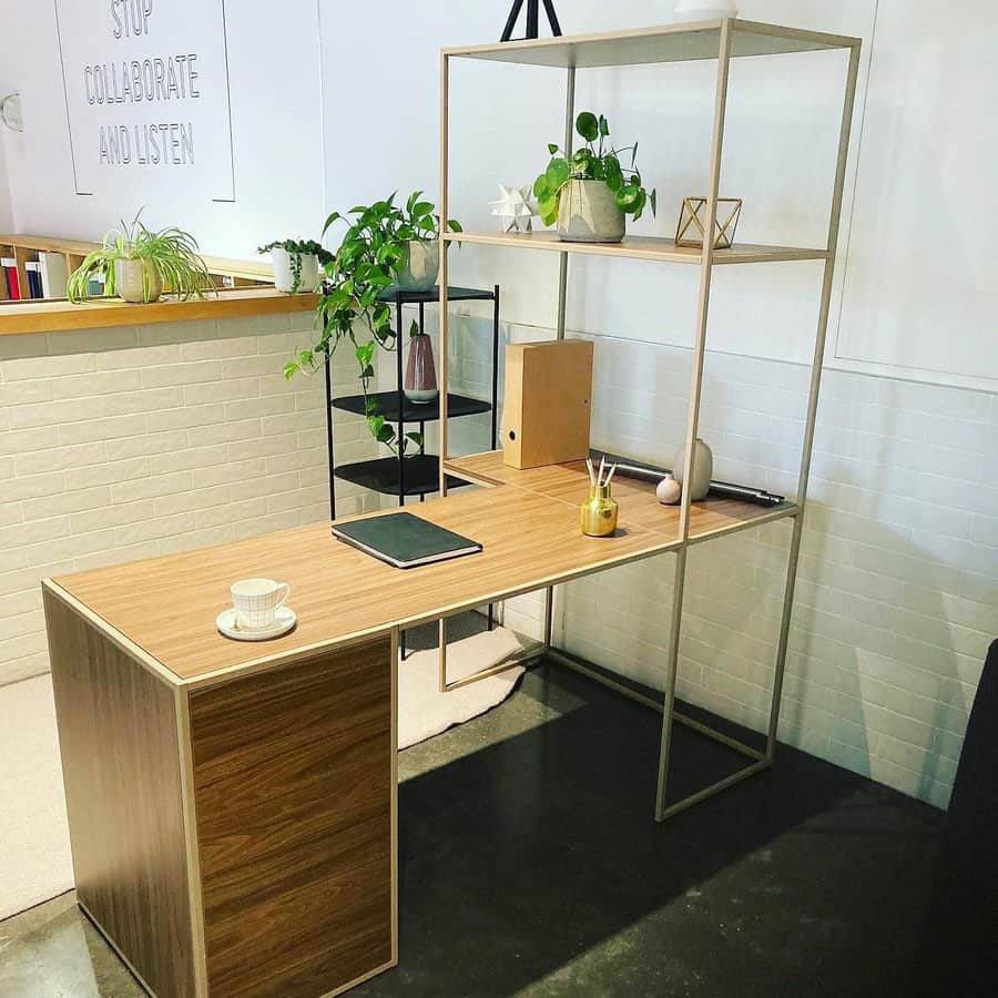 Modern office desk with plants, a tablet, coffee cup, and stationery set against a white wall with motivational text