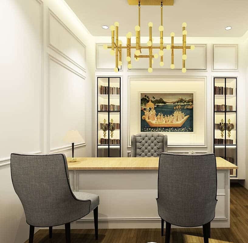 Elegant office with a wooden desk, two gray chairs, a tufted armchair, bookshelf, artwork, and modern gold chandelier