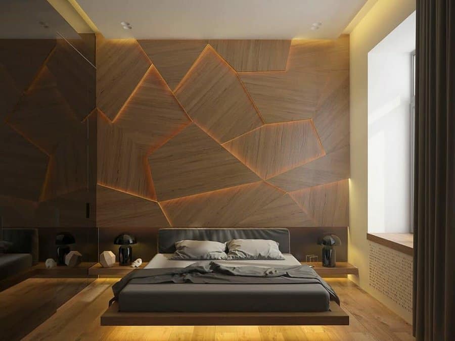 Modern bedroom with geometric wooden wall panels, a low bed, and soft lighting; large window on the right enhances brightness