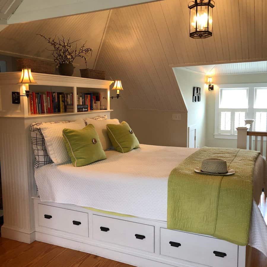 Cozy attic bedroom with a built-in storage bed, bookshelf headboard, soft lighting, and a bright, airy design with green accents.