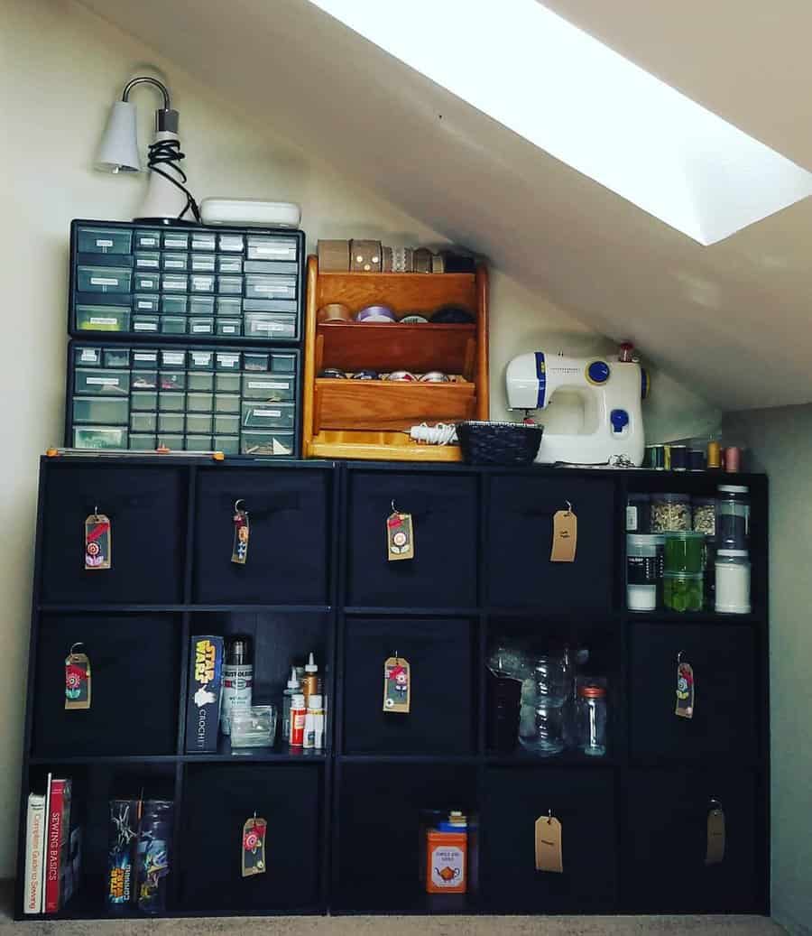 Organized attic craft station with labeled storage bins, a sewing machine, and a skylight, maximizing space under a sloped ceiling.