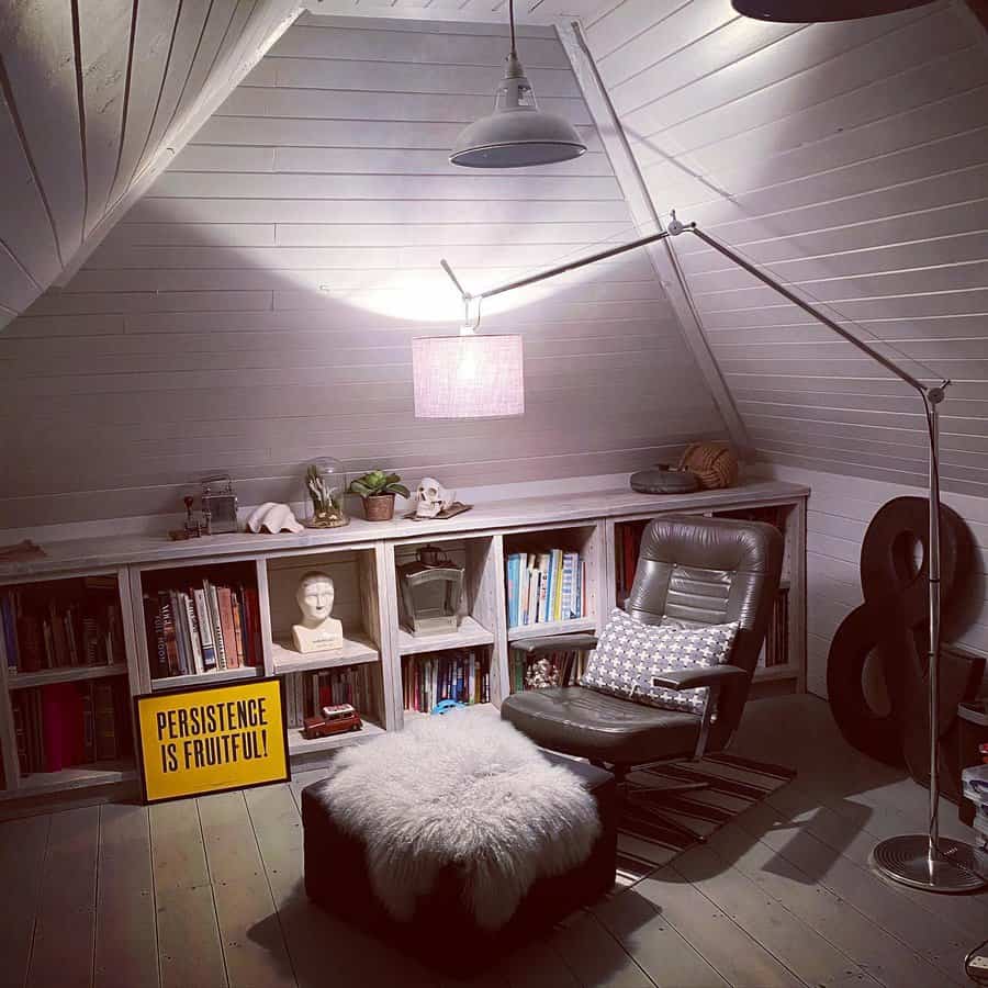 Cozy attic reading nook with built-in bookshelves, a leather lounge chair, soft lighting, and a warm, rustic ambiance.