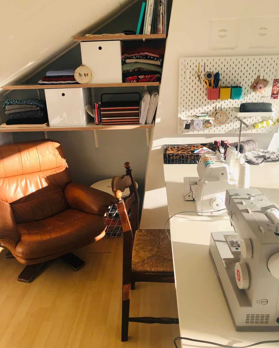 Cozy attic sewing workspace with a pegboard organizer, built-in shelves for fabric storage, and a bright, inviting setup for crafting.