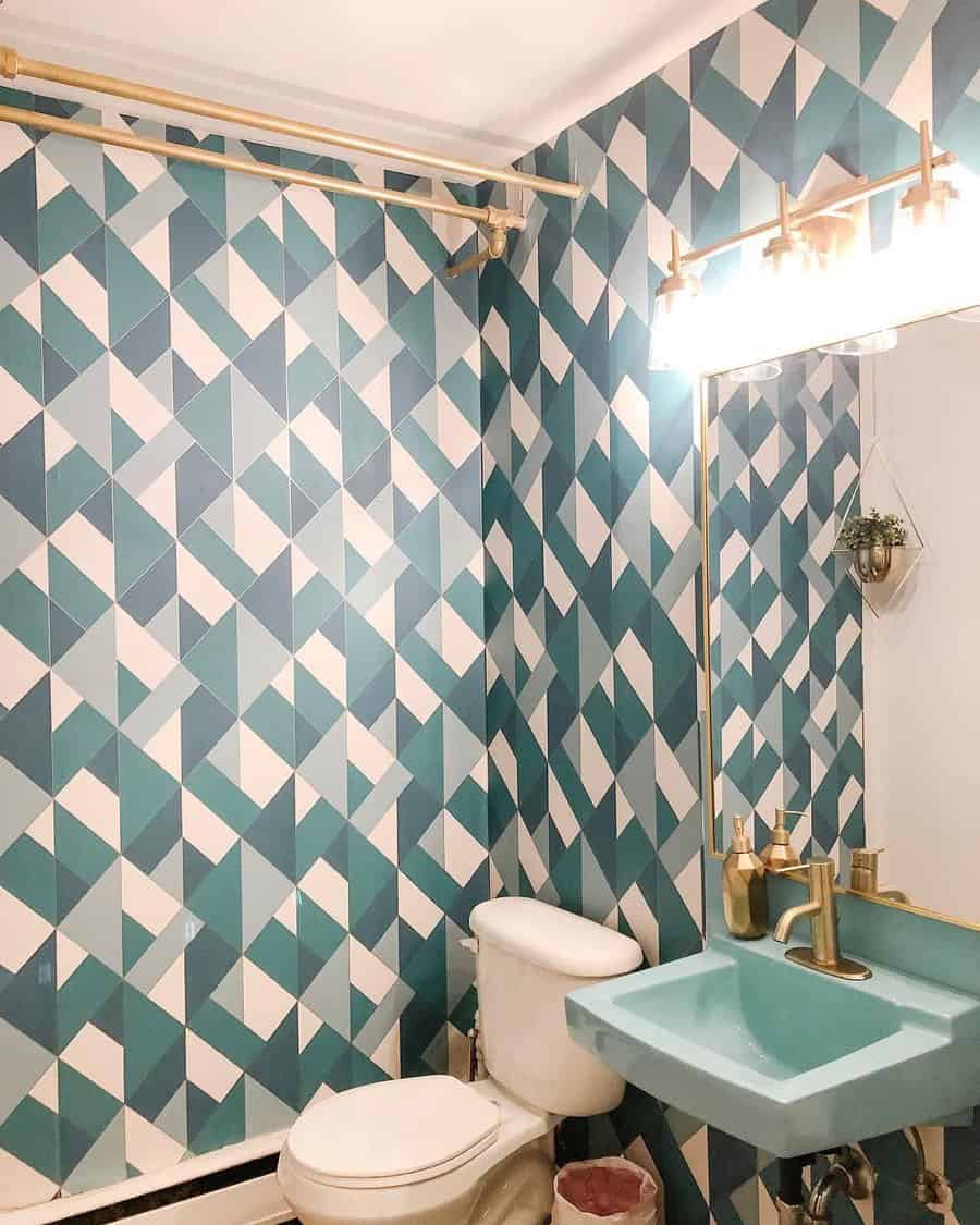 Bathroom with blue and white geometric tile wall, gold fixtures, a white toilet, and a turquoise sink under a large mirror