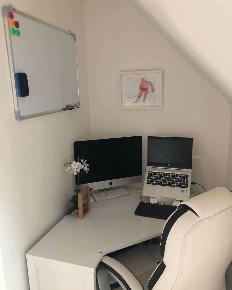 Compact office nook with a desk, iMac, laptop on a stand, whiteboard, orchid plant, and a framed picture in neutral tones and cozy setup