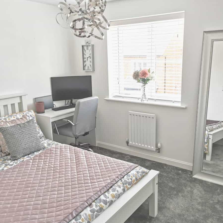 Bright bedroom office with a compact white desk, grey chair, and soft pink bedding, blending elegance and functionality in a cozy space