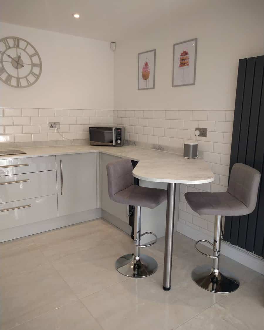 Compact kitchen with a corner breakfast bar, grey barstools, white subway tiles, and a cozy, modern aesthetic