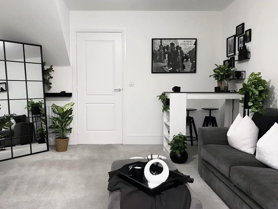 Stylish corner breakfast bar in a modern black-and-white living space, featuring barstools, built-in shelves, and lush green plants