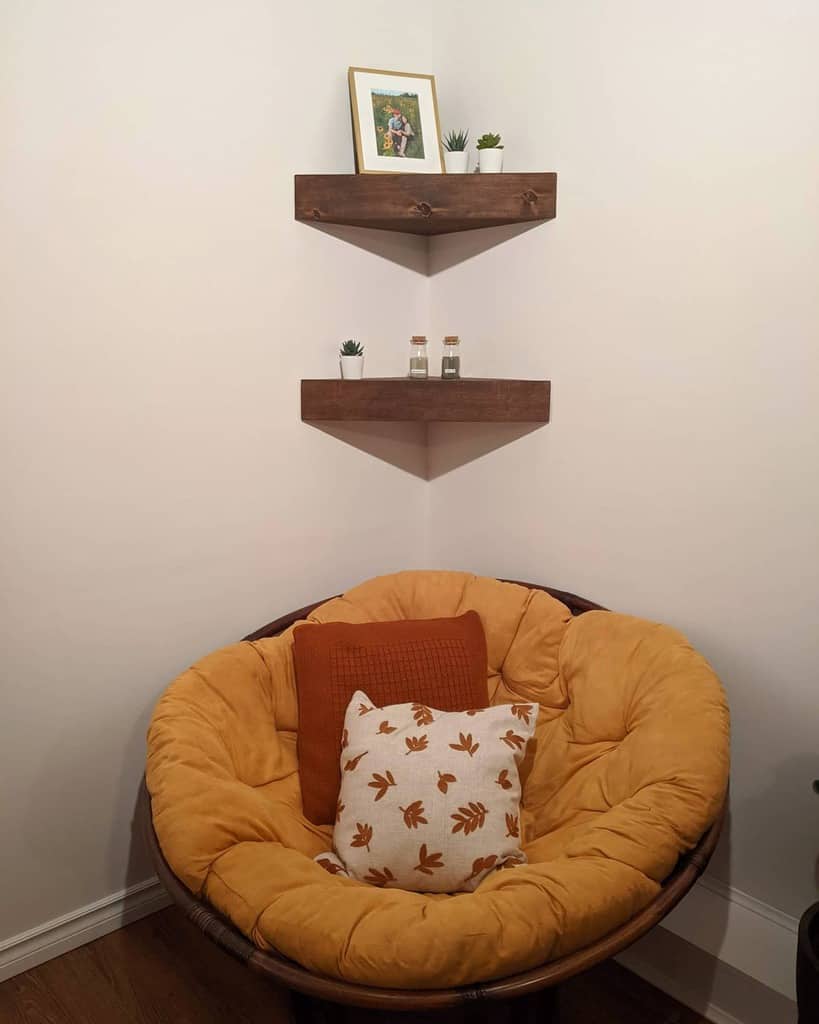 Cozy corner nook with rustic wooden floating shelves, small plants, and a framed photo above a plush mustard-yellow papasan chair