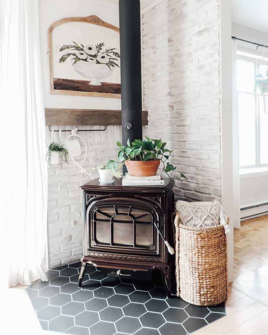 Bright and airy corner wood stove with a whitewashed brick hearth, black hexagon tile flooring, and cozy farmhouse decor for a charming touch.