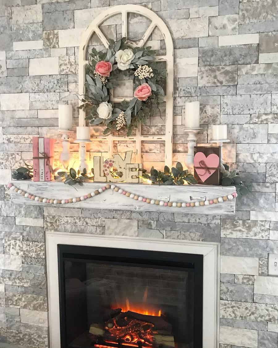 Cozy fireplace with a stone surround, decorated with candles, a floral wreath, and heart ornaments on the mantel