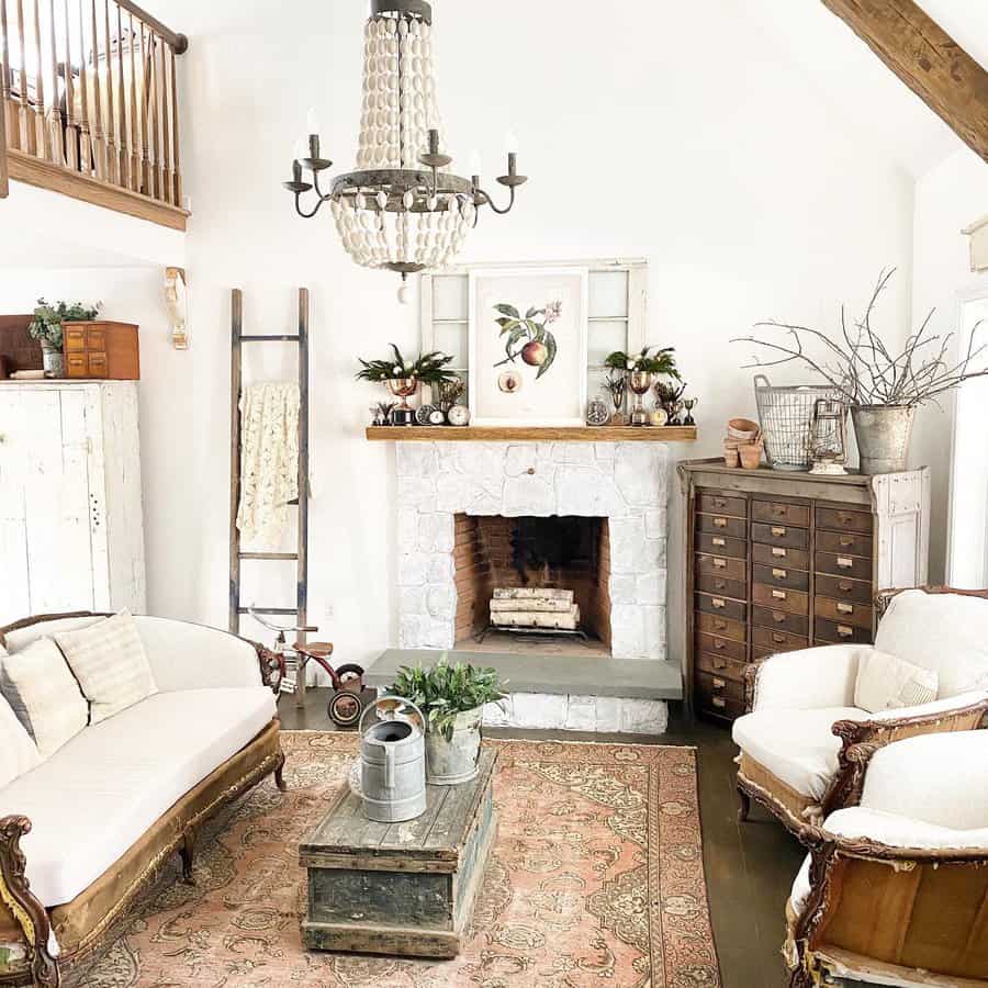 Cozy living room with vintage sofas, a stone fireplace, ladder decor, rustic chandelier, and a wooden chest creates a warm, inviting atmosphere