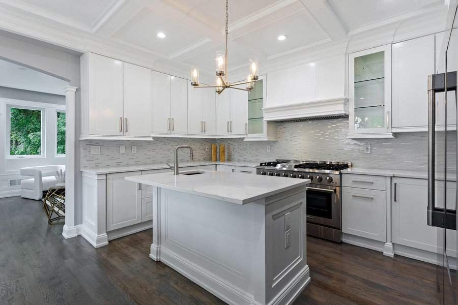 Modern white kitchen with an island, stainless steel appliances, and hardwood floors