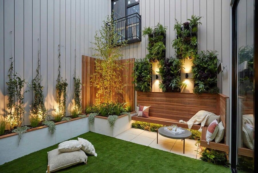 Stylish courtyard with vertical garden, built-in wooden seating, ambient lighting, artificial turf, and cozy decor accents