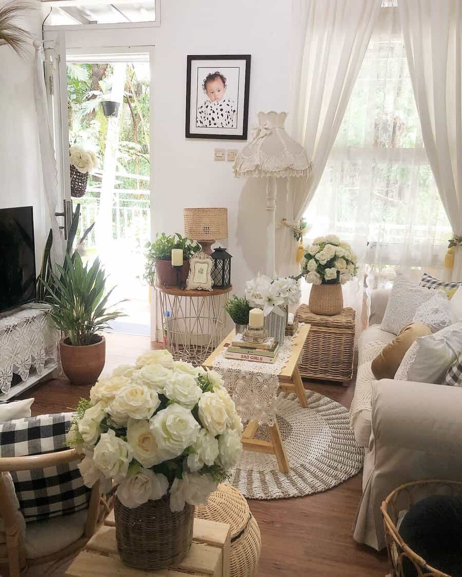 Charming cottage-style living room with soft neutrals, lace details, wicker accents, and fresh white roses creating a cozy, inviting atmosphere