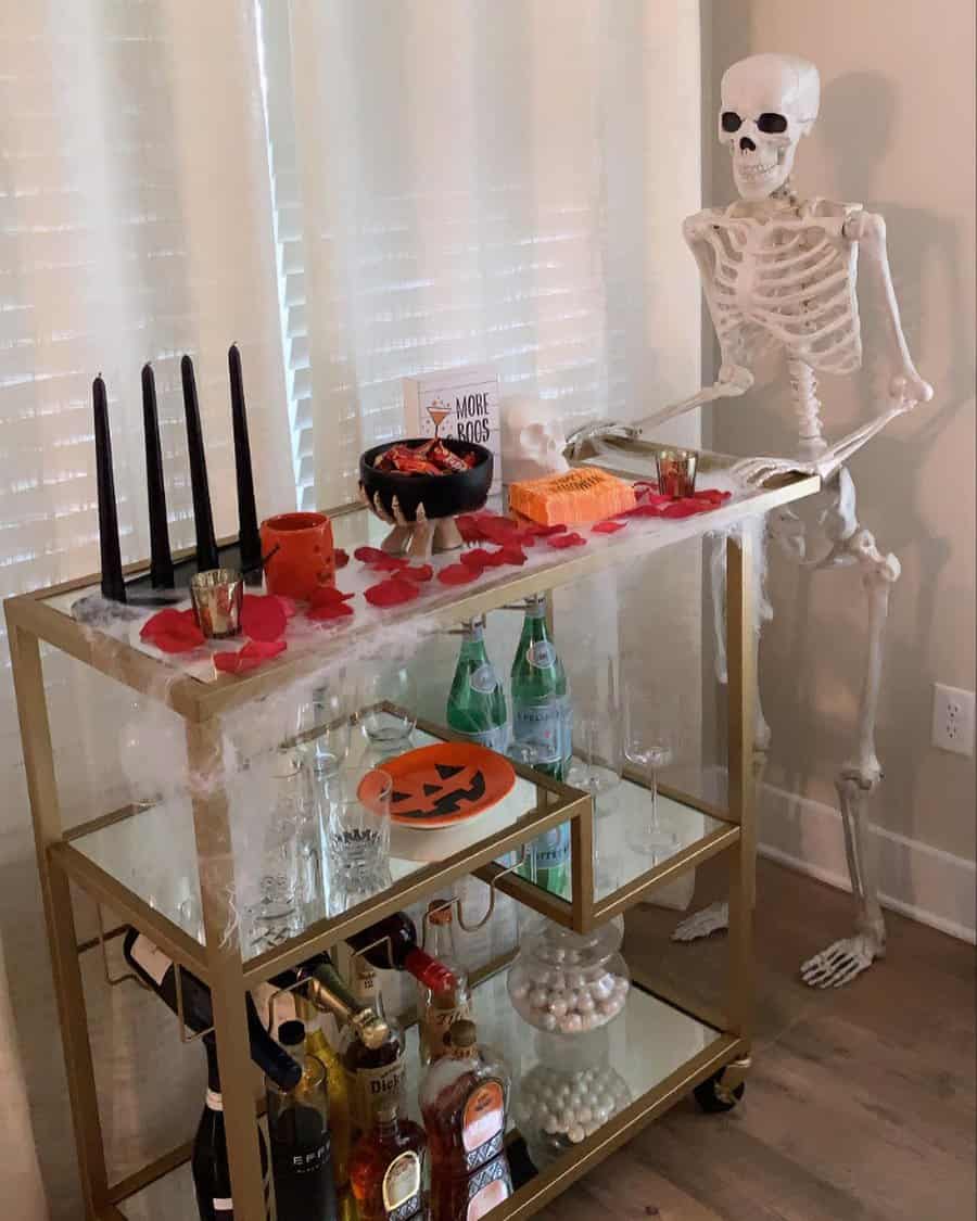 Gold bar cart with Halloween drinks and snacks, decorated with a skeleton and cobwebs