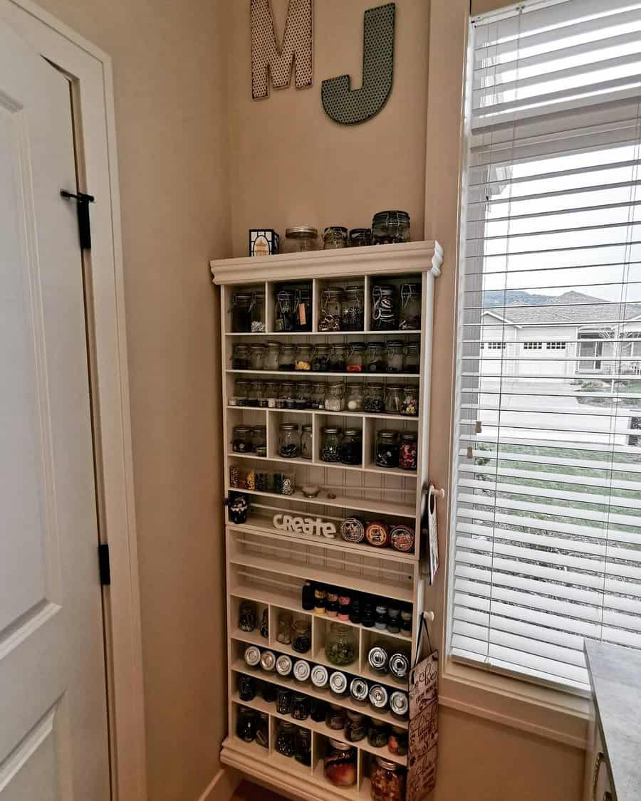 Tall shelf with jars of craft buttons by window