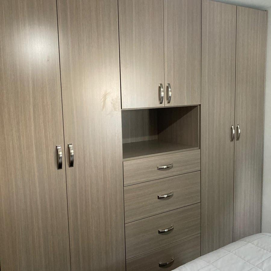 Wooden wardrobe with silver handles, featuring two large cabinets, three central drawers, and an open compartment