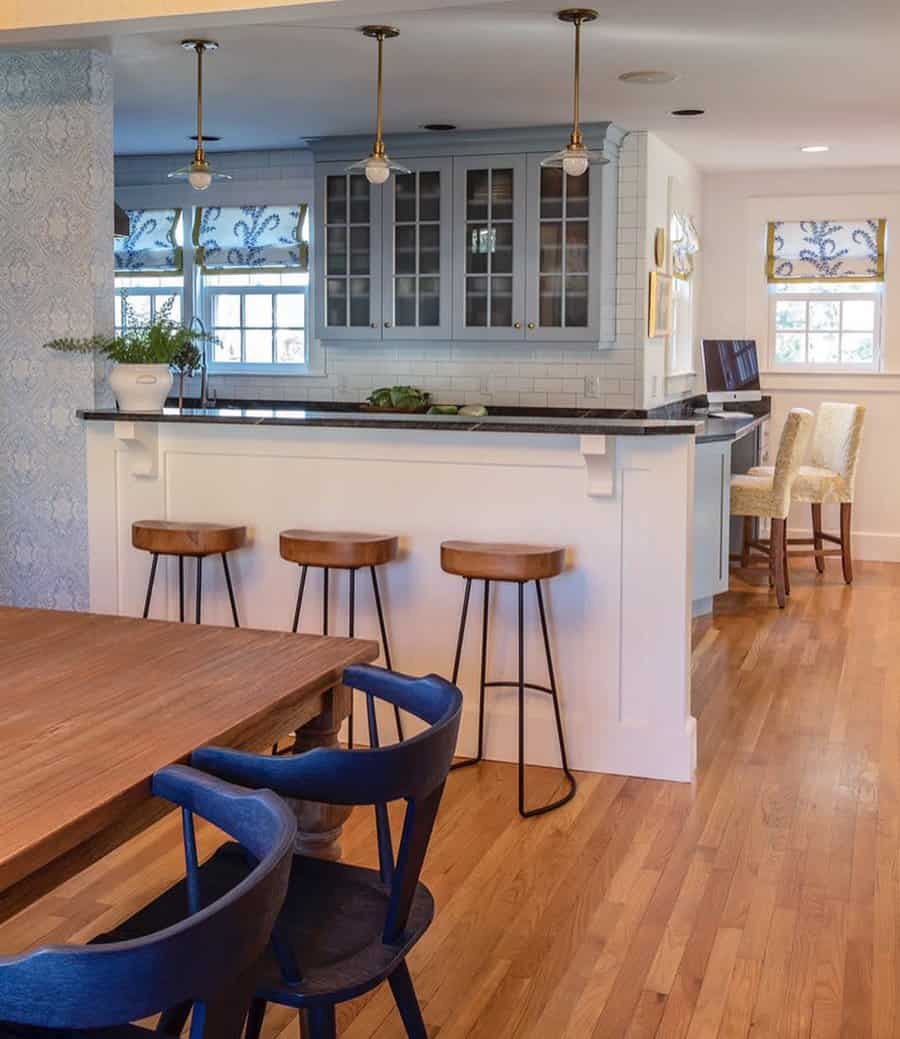 Charming kitchen with a half-wall breakfast bar, wooden stools, soft blue cabinetry, and pendant lighting for a cozy, classic feel