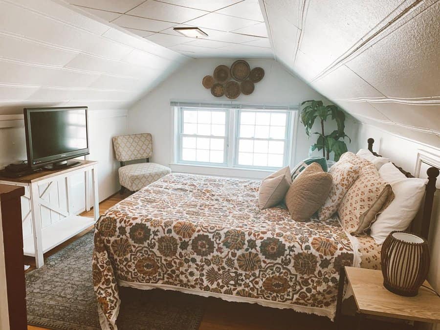 Cozy attic bedroom with warm boho decor, floral bedding, and natural wood accents. Soft lighting and vintage details create a charming retreat.