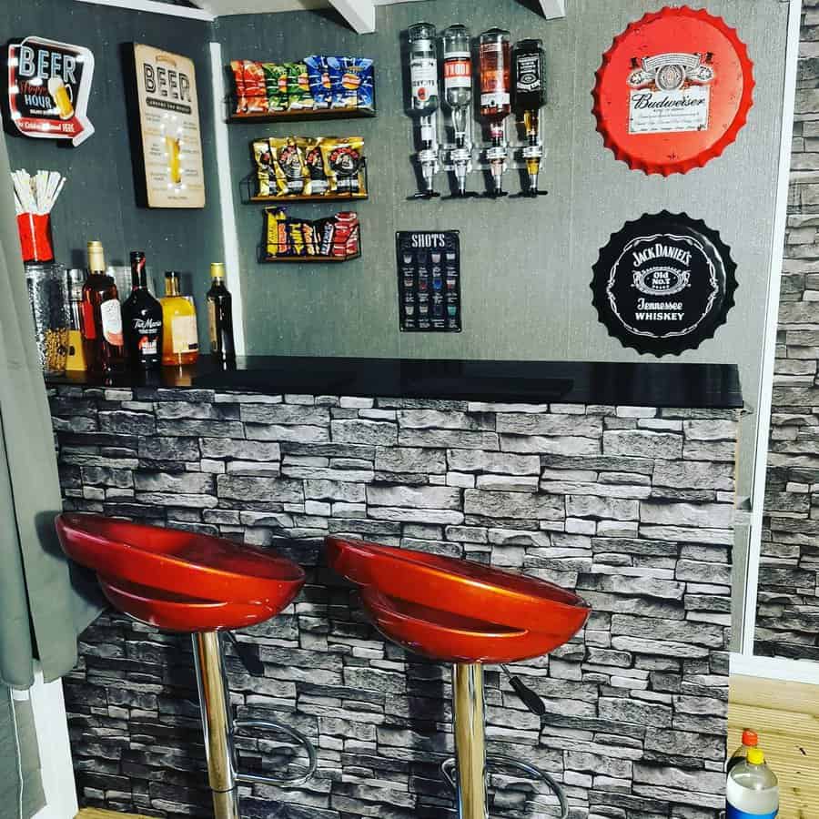 Home bar with a brick-style counter, red bar stools, liquor bottles, snacks, and drink dispensers on display; wall decorations include beer signs