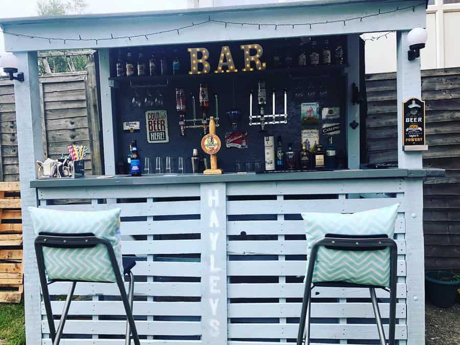 Chic backyard bar with light up sign and patterned stools