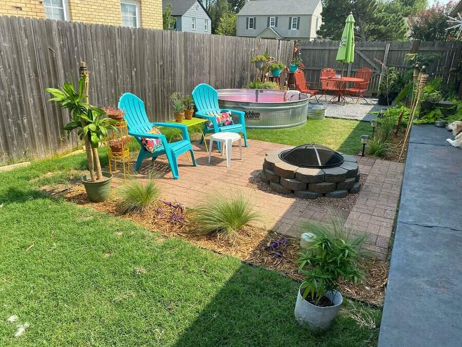 Backyard with teal chairs, fire pit, small pool, plants, and patio set under a green umbrella