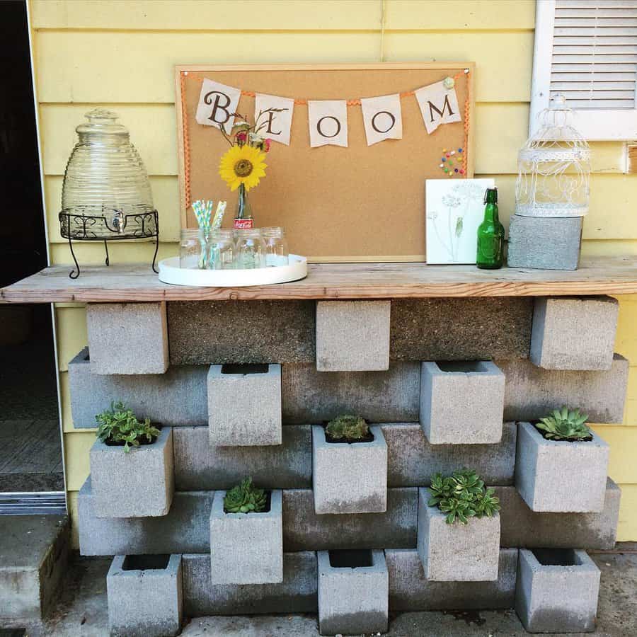 Rustic DIY cinder block bar with built-in succulent planters, a wooden countertop, and charming decor, creating a functional and stylish outdoor space