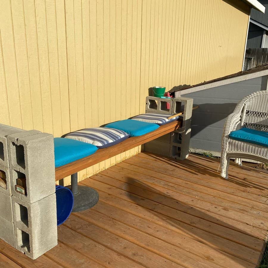 DIY cinder block bench with wooden seating and blue-striped cushions, creating a cozy and functional outdoor seating area on a wooden deck