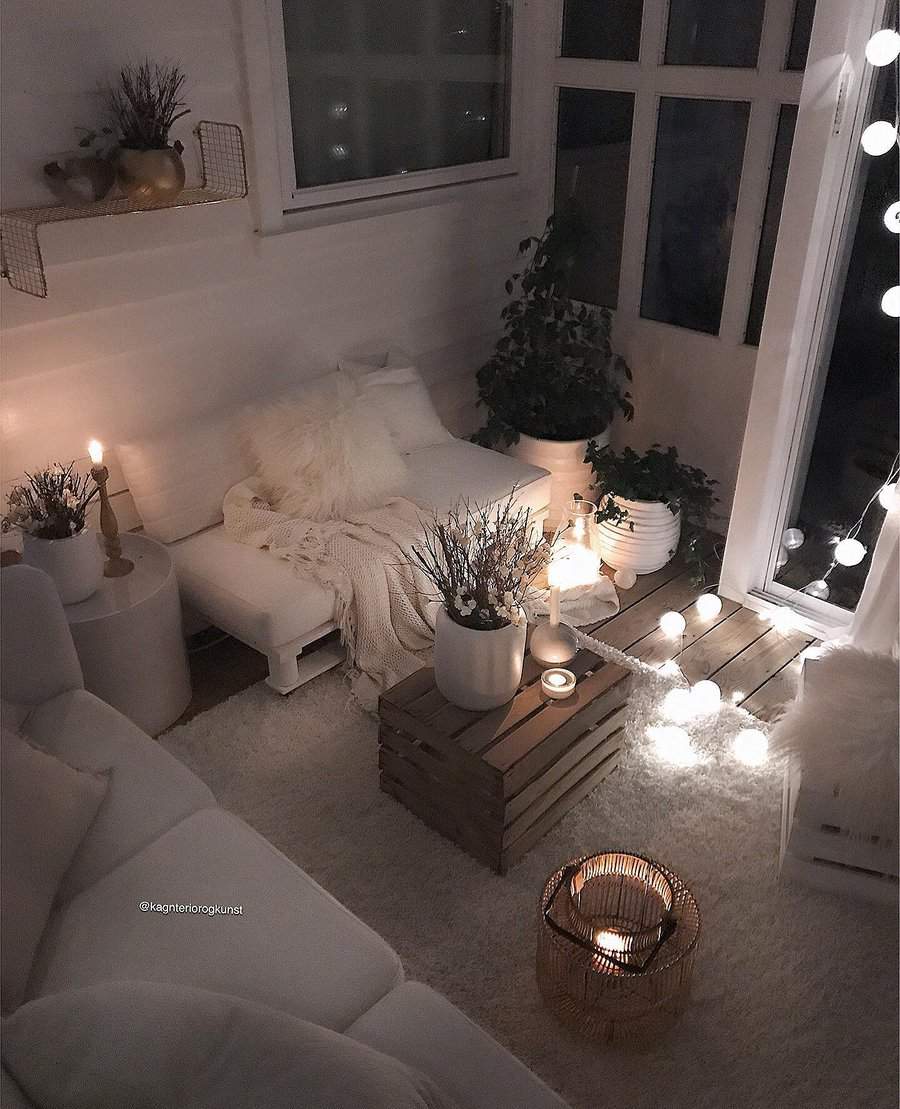 Cozy DIY daybed nook with soft blankets, warm candlelight, and string lights, creating a serene and inviting atmosphere for relaxation