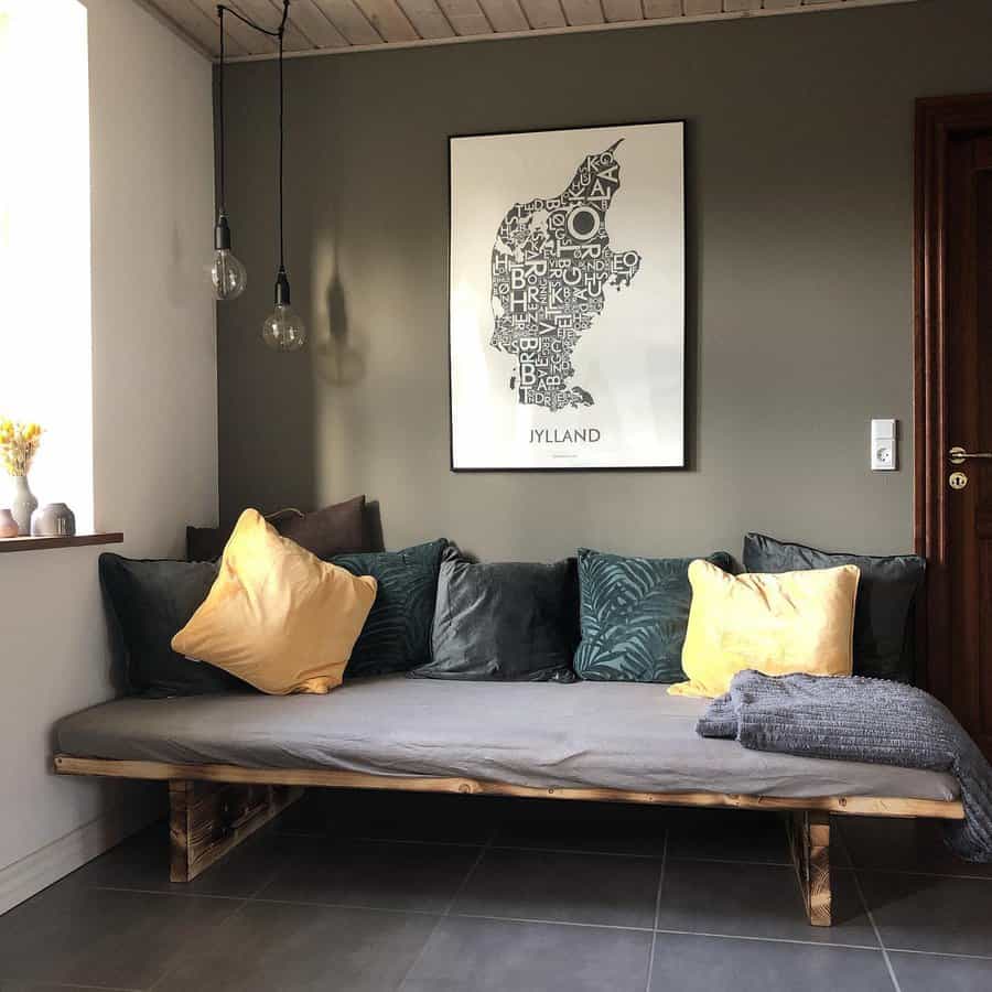 Minimalist DIY daybed with a rustic wooden base, gray cushions, and warm-toned pillows, creating a cozy and stylish lounge corner