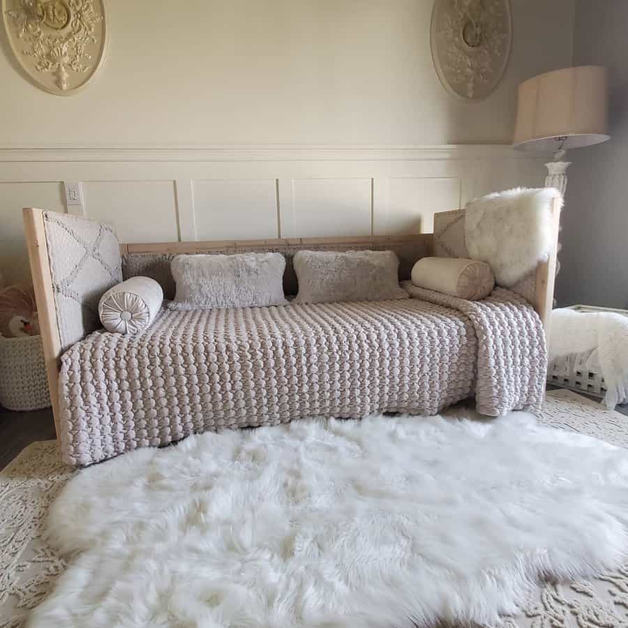 Stylish daybed with a textured blanket, plush pillows, and a fluffy white rug in a cozy, warmly decorated room