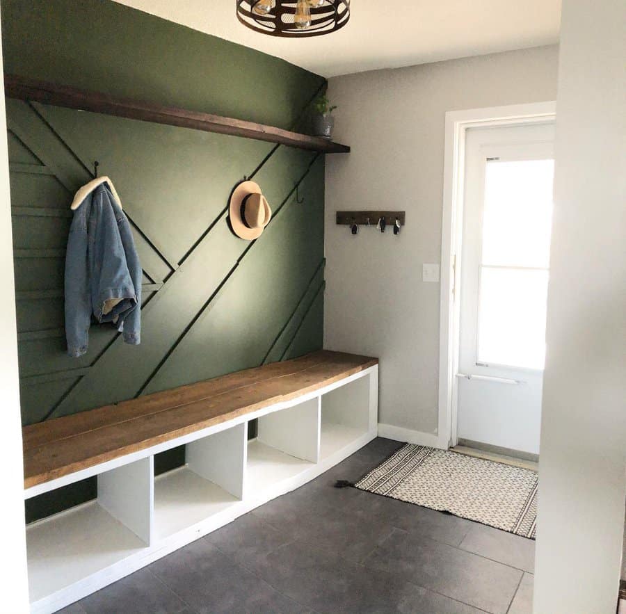 Modern farmhouse entryway with a bold green accent wall, built-in wooden bench with storage, and rustic hooks, creating a stylish and functional space