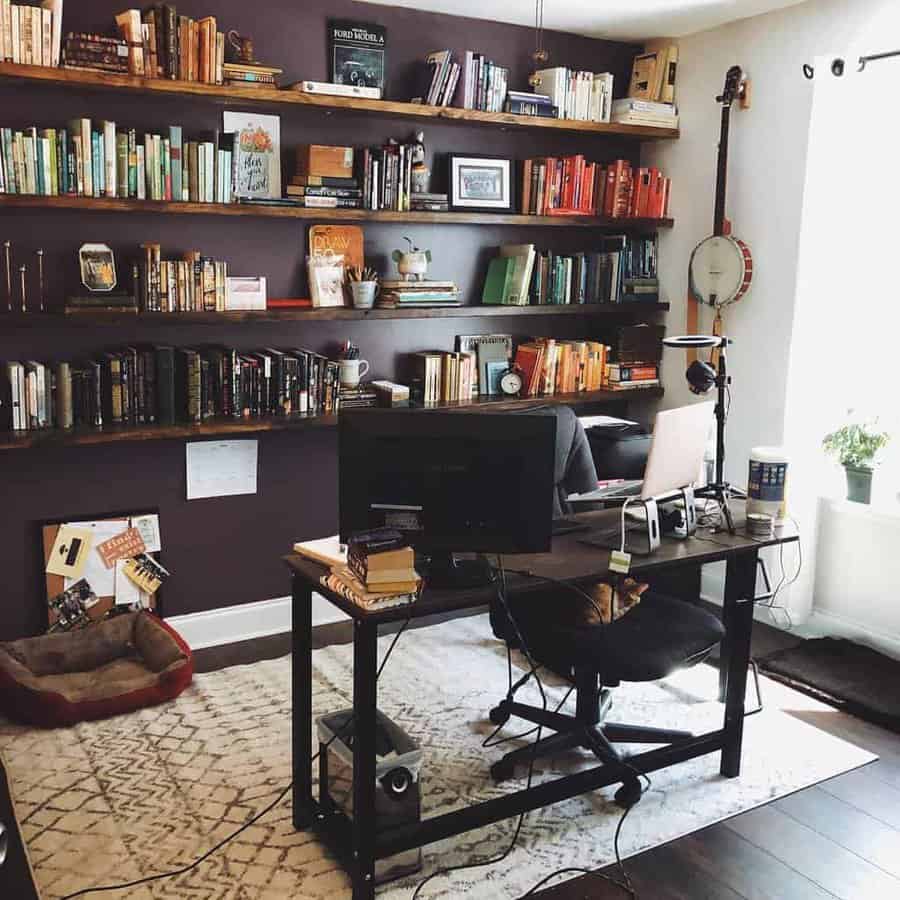 Home office with dark floating bookshelves, an industrial desk, and a cozy reading nook, creating a warm and creative workspace