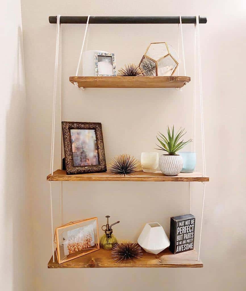 Three-tiered hanging shelves with photos, plants, decor items, and books set against a light wall: Cozy and decorative display