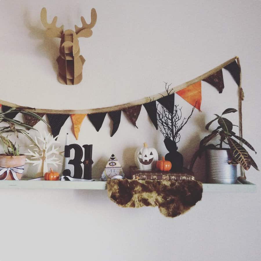 Halloween-themed shelf with pumpkins, decorations, and a mounted deer head above