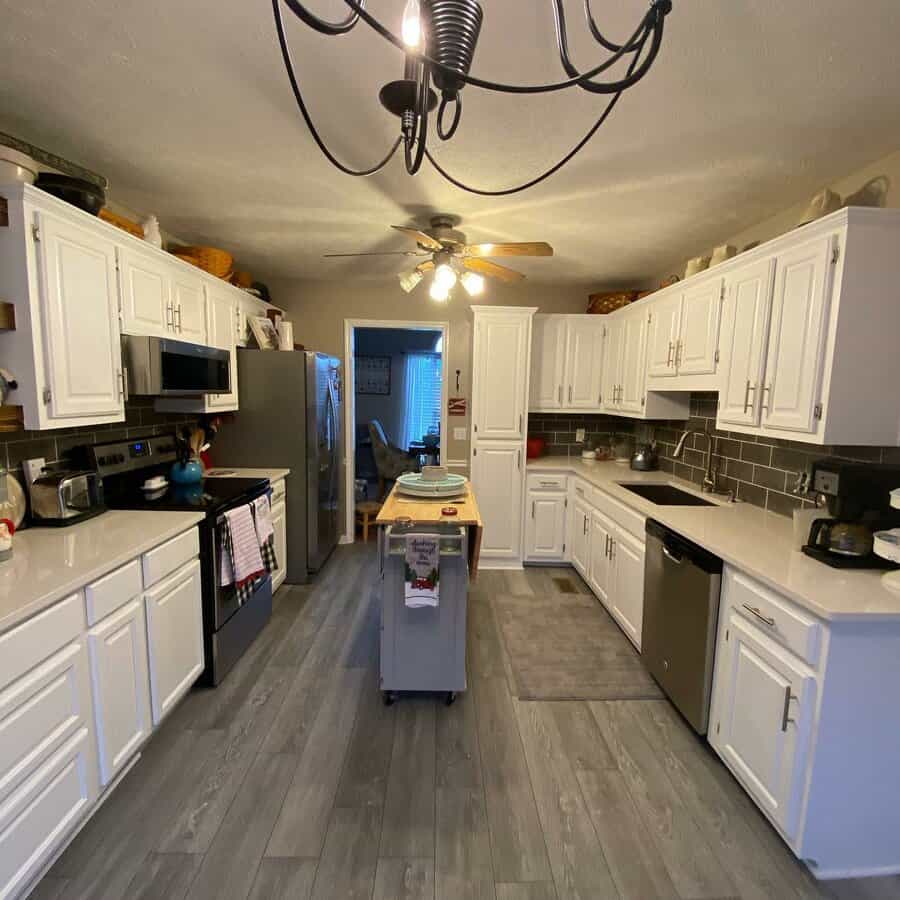 A kitchen with white cabinets and gray floor tiles