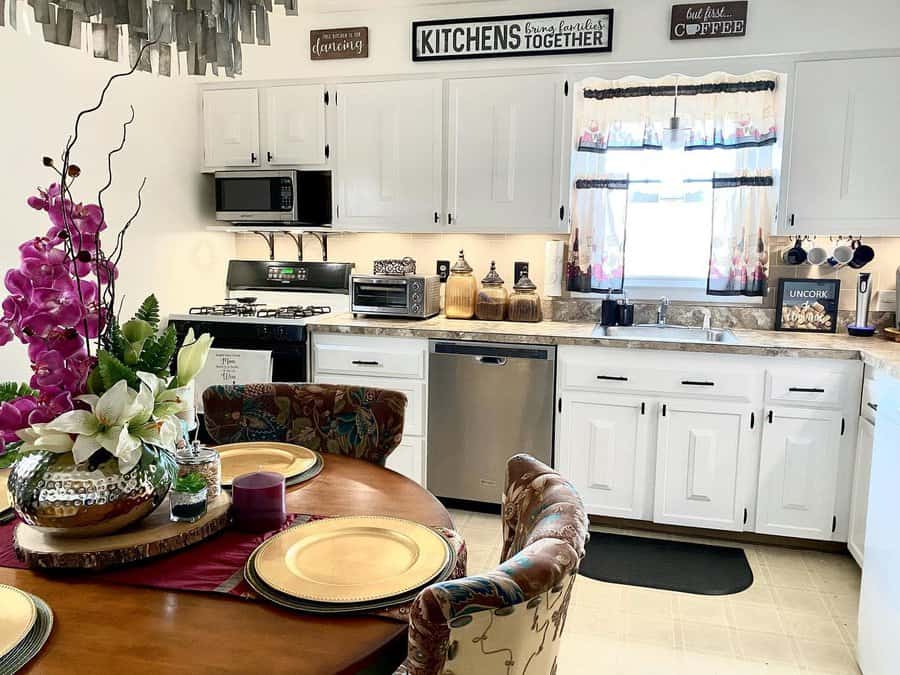 Cozy kitchen with white cabinets, decorative signs, floral centerpiece, and a dining table set for a warm and inviting atmosphere