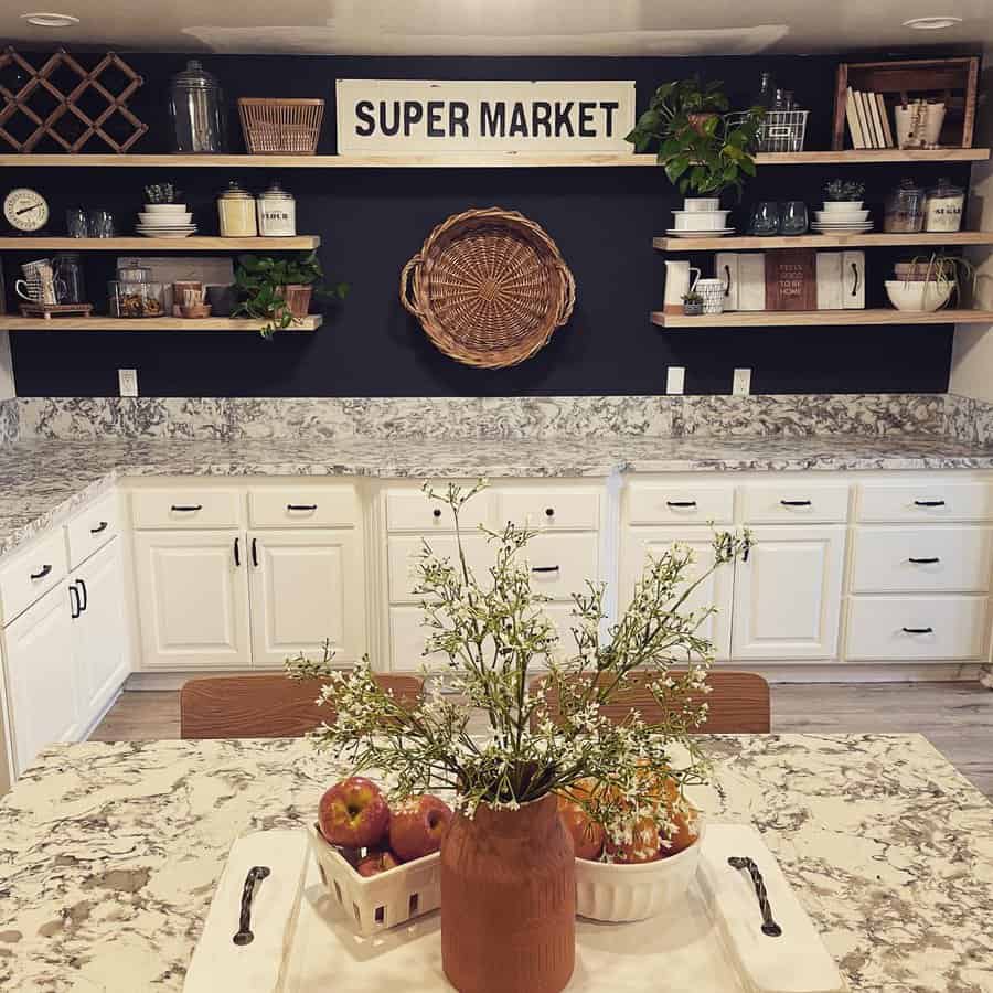 Rustic farmhouse kitchen with white cabinets, marble countertops, open shelves, and a cozy dining space with a floral centerpiece