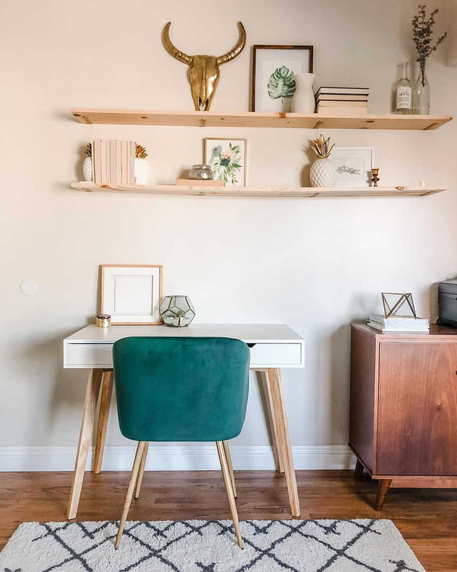 Minimalist home office with a white desk, green chair, floating shelves, and decor items like a gold bull skull and plants