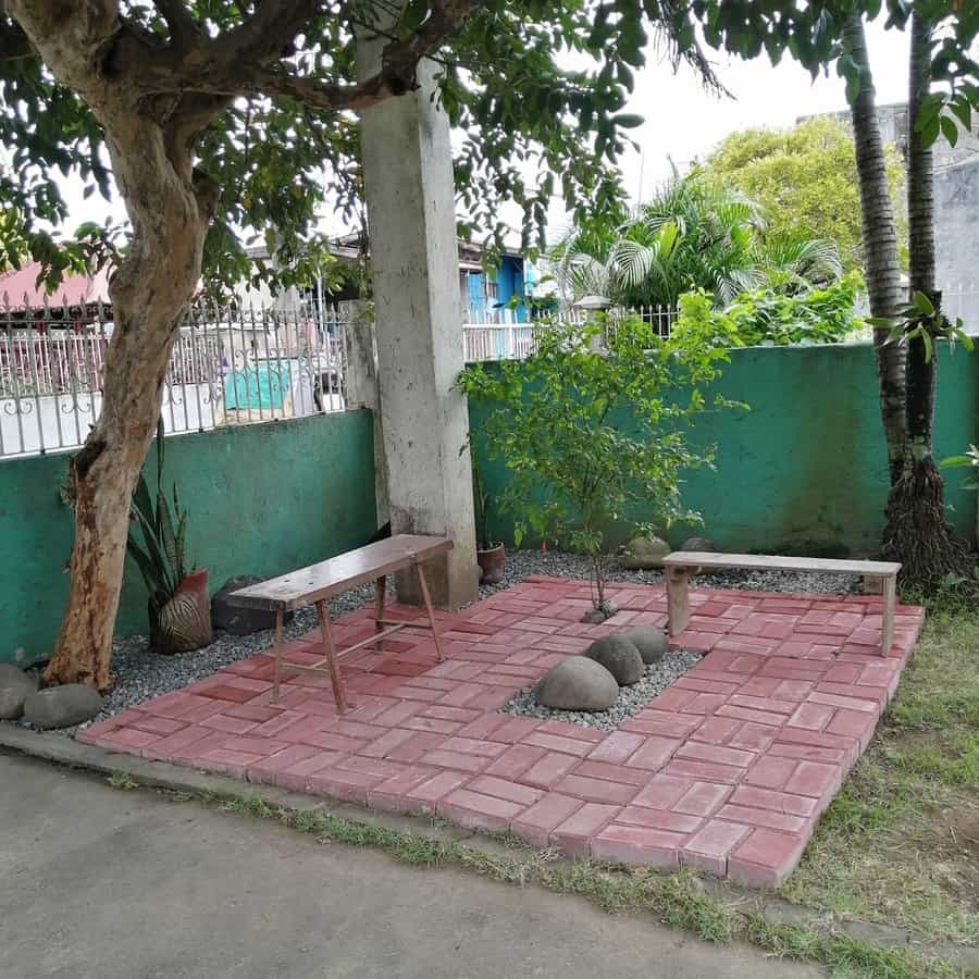 Outdoor corner with red stone patio and wooden bench