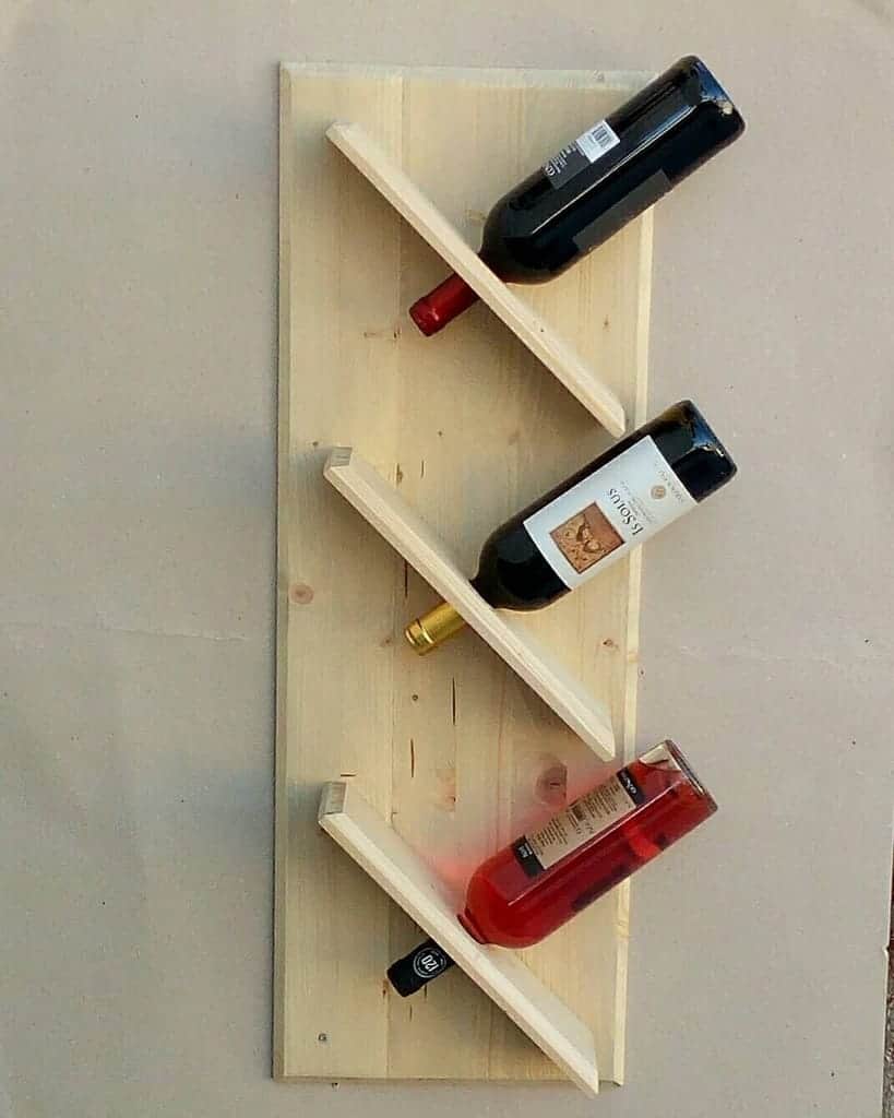 Wooden wall-mounted wine rack holding four bottles in an angled pattern