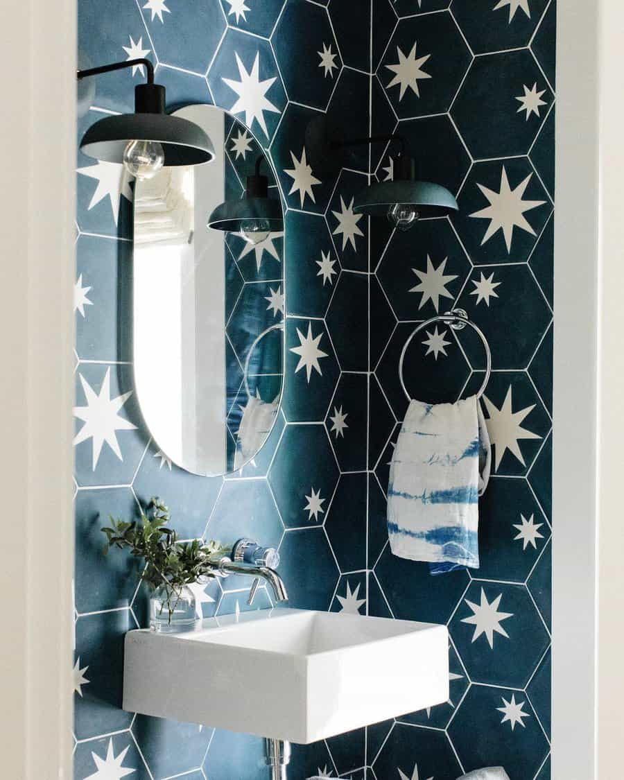 Bold bathroom with navy hexagon star tiles, modern white sink, wall-mounted faucet, and black sconces for a celestial vibe.