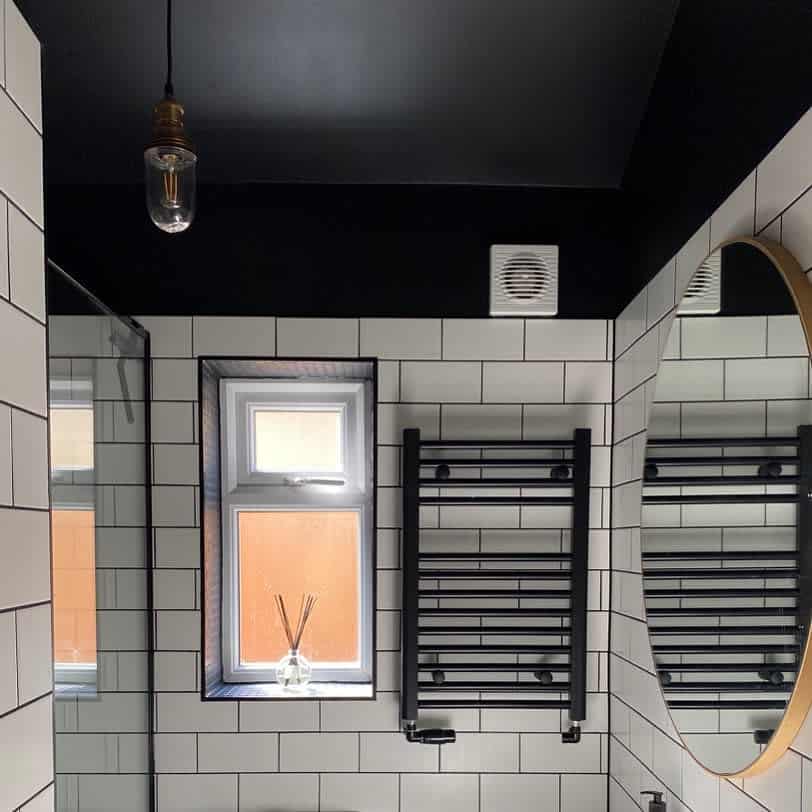 Modern bathroom with a bold black ceiling, white subway tiles, and black fixtures, creating a sleek monochrome contrast with an industrial touch.