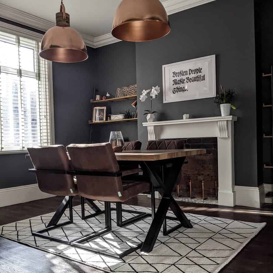 Dining room with dark walls, a wooden table, cushioned chairs, geometric rug, and copper pendant lights near a window