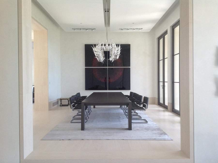 Modern dining room with a long black table, sleek black chairs, large abstract wall art, and an artistic white chandelier