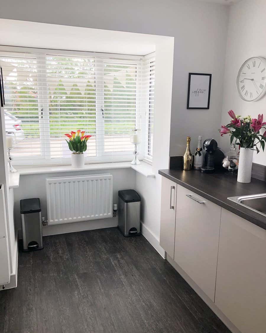 Dark wood-style kitchen flooring creates a striking contrast with white cabinetry, adding warmth and sophistication to this bright, modern space